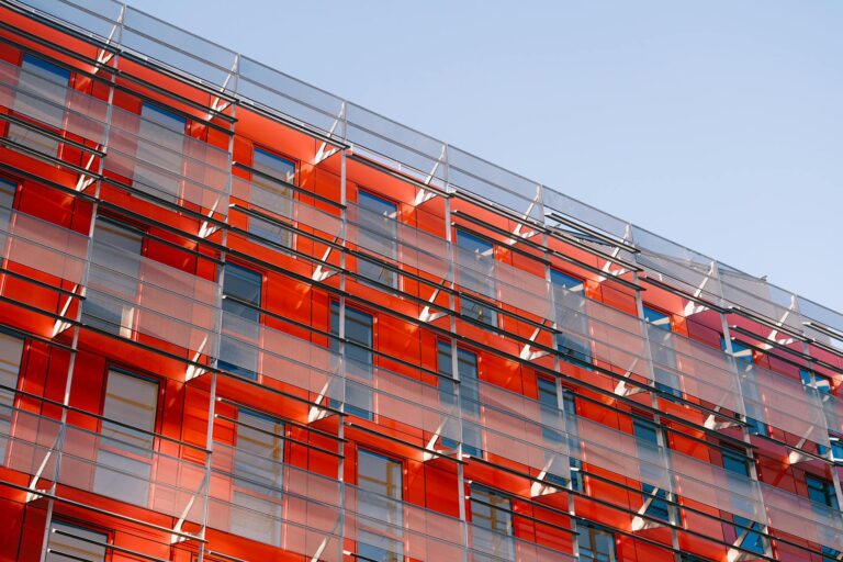 Striking red glass facade showcasing modern urban architecture under clear skies.