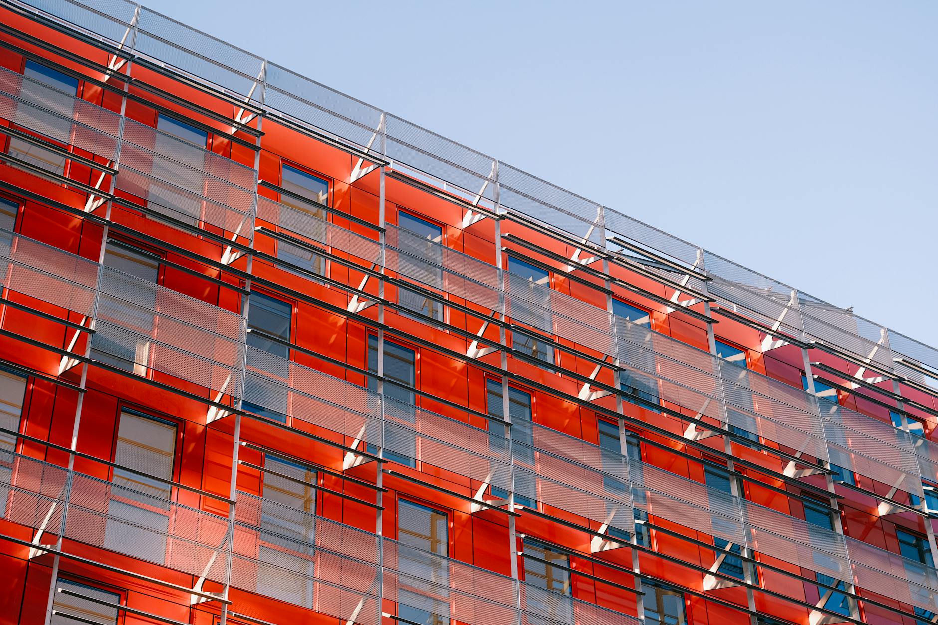 Striking red glass facade showcasing modern urban architecture under clear skies.