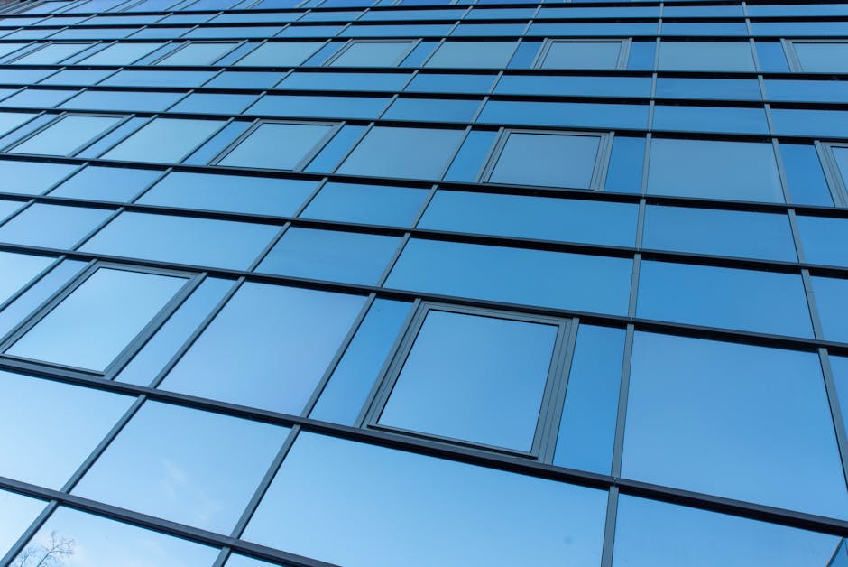A sleek and reflective blue glass facade of a modern office building demonstrating architecture's clean lines and minimalism.