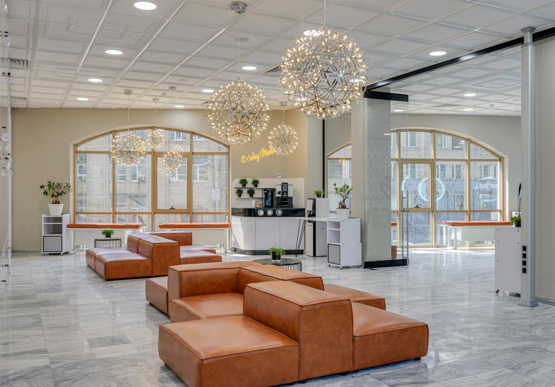 Spacious office lobby featuring stylish leather seating and stunning chandeliers.